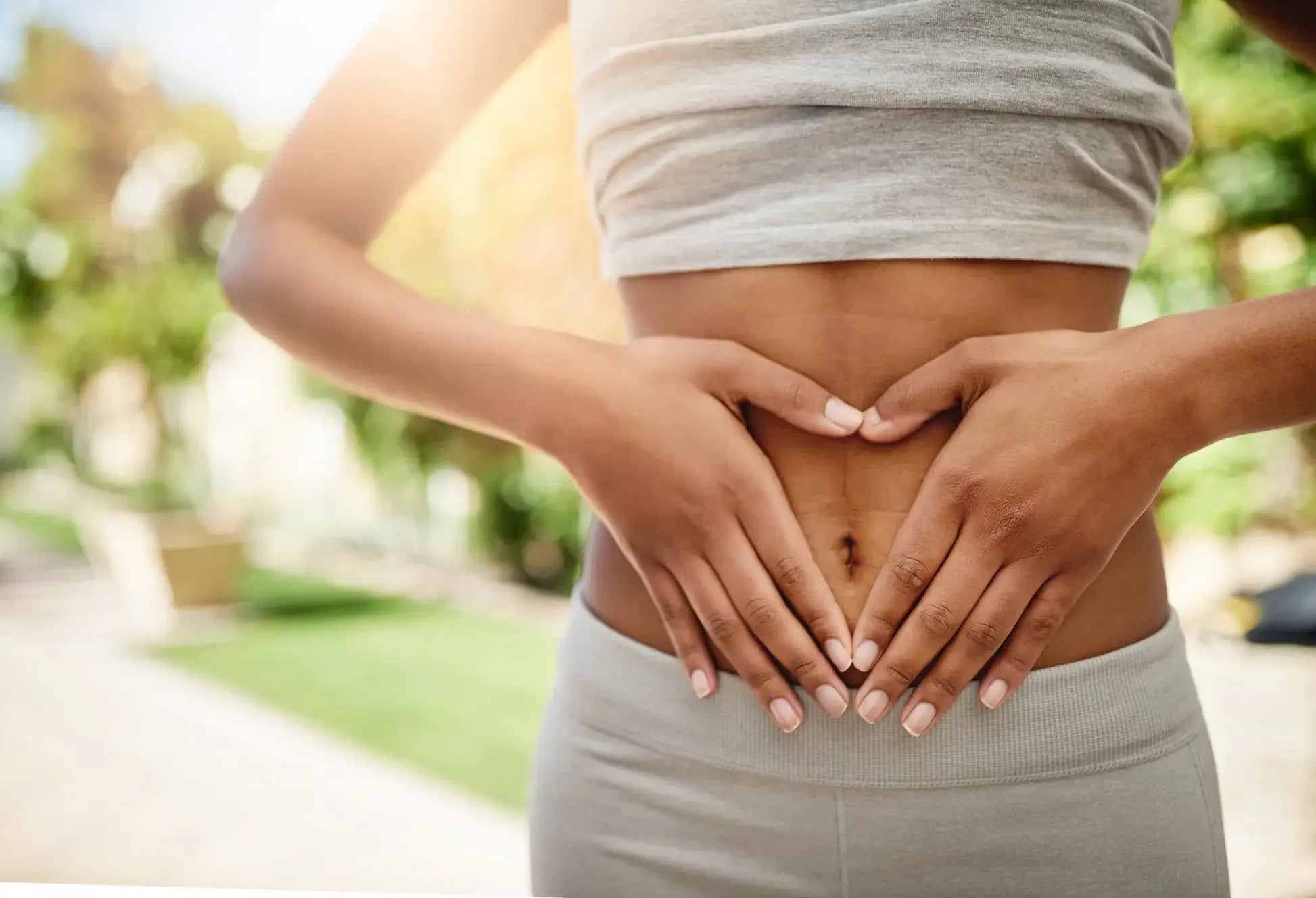 Person holding their stomach with hands outdoors